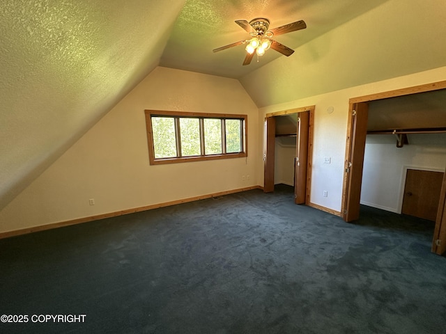 10821 E Valley Crest Dr, Palmer, AK 99645 - unfurnished bedroom with two closets, lofted ceiling, dark colored carpet, a textured ceiling, and ceiling fan