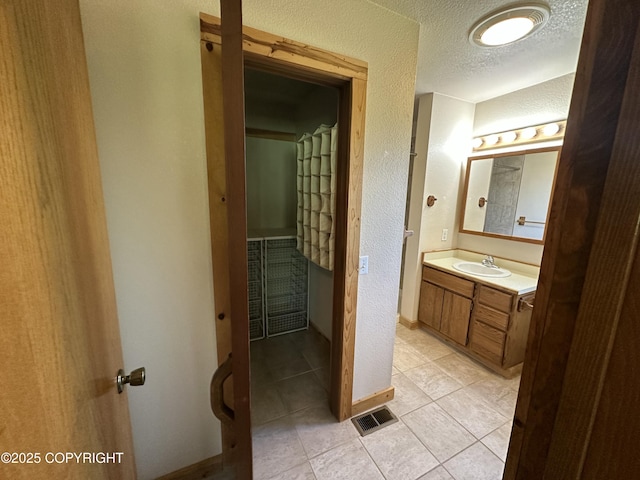10821 E Valley Crest Dr, Palmer, AK 99645 - bathroom with vanity, a textured ceiling, tile patterned floors, and a textured wall