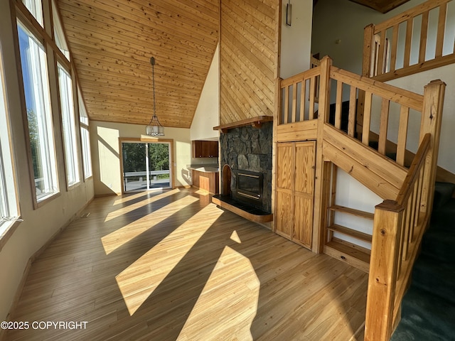 10821 E Valley Crest Dr, Palmer, AK 99645 - unfurnished living room with light wood-type flooring, high vaulted ceiling, stairway, and a stone fireplace