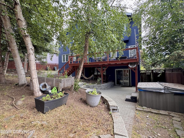 13404 Mainsail Dr, Anchorage, AK 99516 - back of property featuring a hot tub, a vegetable garden, a wooden deck, and a patio area