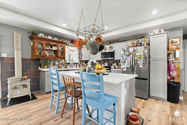 5050 N Gold Mint Dr, Wasilla, AK 99654 - kitchen featuring appliances with stainless steel finishes, a wood stove, light countertops, light wood-style floors, and a center island