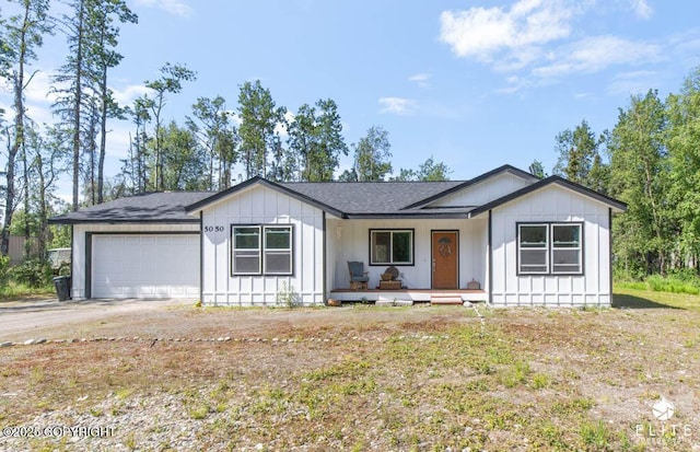 5050 N Gold Mint Dr, Wasilla, AK 99654 - view of front of home featuring an attached garage, a porch, dirt driveway, board and batten siding, and roof with shingles