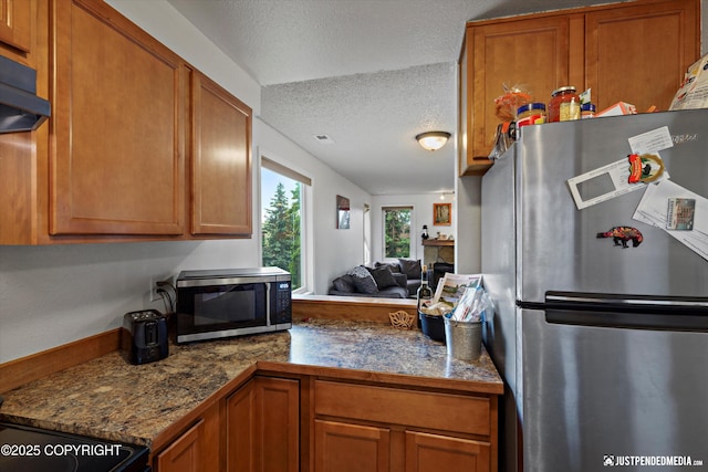 10201 Jamestown Dr # A102, Anchorage, AK 99507 - kitchen featuring appliances with stainless steel finishes, brown cabinets, a textured ceiling, range hood, and open floor plan
