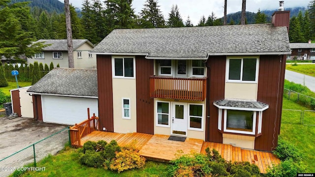 5920 Lund St, Juneau, AK 99801 - view of front of property featuring a chimney, a shingled roof, a deck with mountain view, an attached garage, and concrete driveway