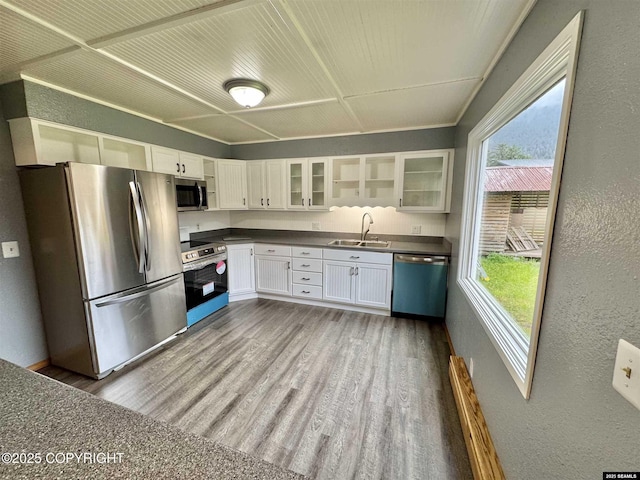 5920 Lund St, Juneau, AK 99801 - kitchen featuring stainless steel appliances, a textured wall, dark countertops, white cabinetry, and glass insert cabinets