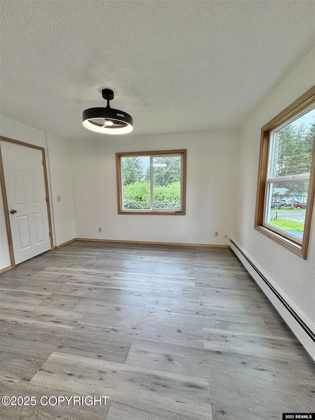 5920 Lund St, Juneau, AK 99801 - unfurnished room featuring a baseboard radiator, healthy amount of natural light, a textured ceiling, wood finished floors, and a ceiling fan