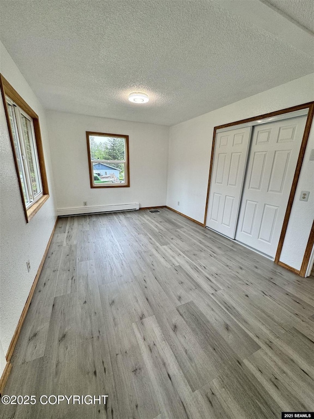 5920 Lund St, Juneau, AK 99801 - unfurnished bedroom featuring wood finished floors, a textured ceiling, baseboard heating, and a closet