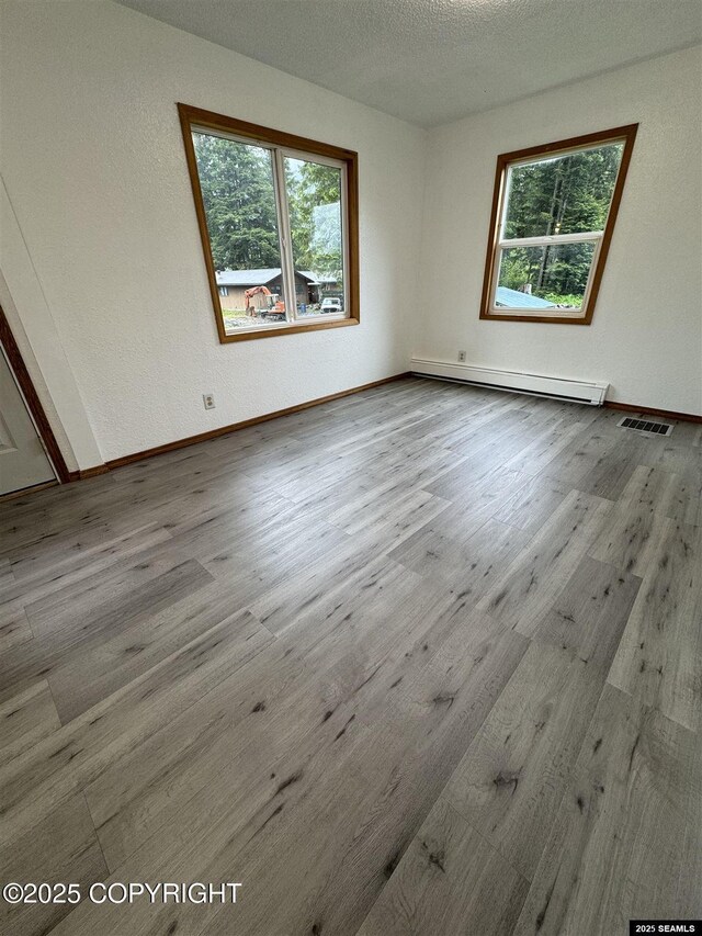 5920 Lund St, Juneau, AK 99801 - spare room featuring a baseboard heating unit, plenty of natural light, wood finished floors, and a textured ceiling