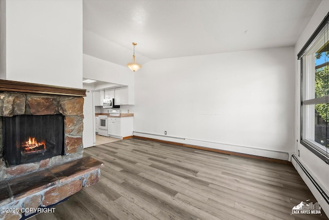 3215 Eastgate Pl # 301, Anchorage, AK 99504 - unfurnished living room with a baseboard heating unit, a fireplace, vaulted ceiling, light wood-type flooring, and a baseboard radiator