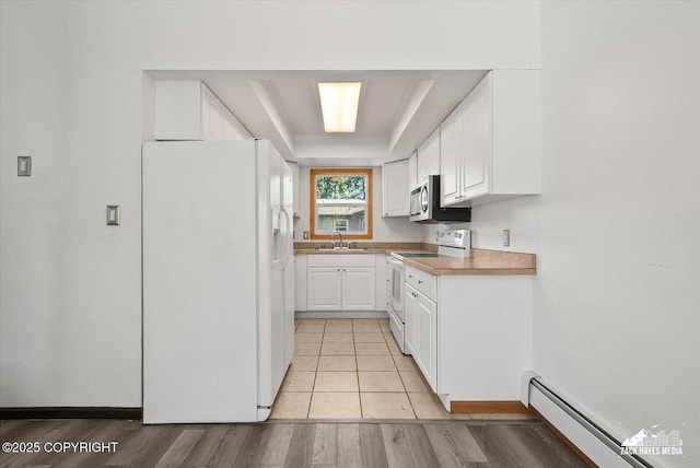 3215 Eastgate Pl # 301, Anchorage, AK 99504 - kitchen with white appliances, a tray ceiling, a baseboard heating unit, white cabinets, and light wood finished floors