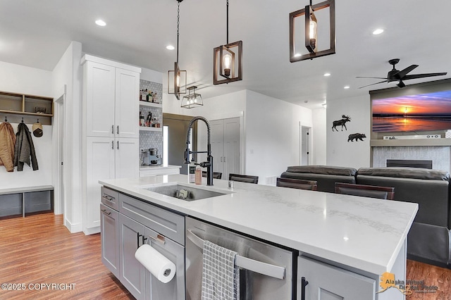 4576 S Gon Fishin Dr, Wasilla, AK 99623 - kitchen featuring dishwasher, ceiling fan, light wood finished floors, open shelves, and a center island with sink