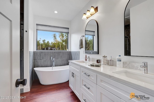 4576 S Gon Fishin Dr, Wasilla, AK 99623 - full bathroom with a soaking tub, double vanity, wood finished floors, tile walls, and a wainscoted wall