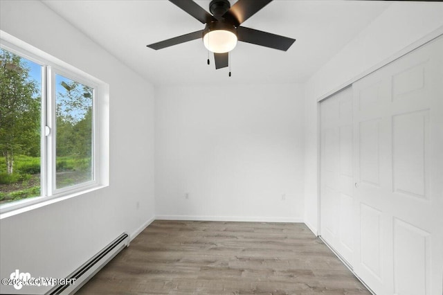 1380 N Cedar Hills Dr, Palmer, AK 99645 - unfurnished bedroom with baseboard heating, multiple windows, wood finished floors, and a closet