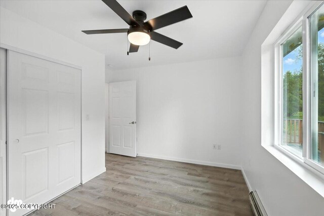 1380 N Cedar Hills Dr, Palmer, AK 99645 - unfurnished bedroom with light wood-type flooring, a closet, baseboard heating, and a ceiling fan