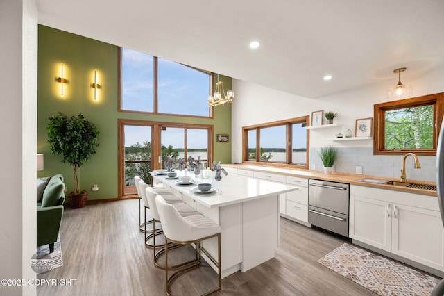 900 W Selina Ln, Wasilla, AK 99654 - kitchen with dishwasher, white cabinets, light wood-style floors, tasteful backsplash, and light countertops