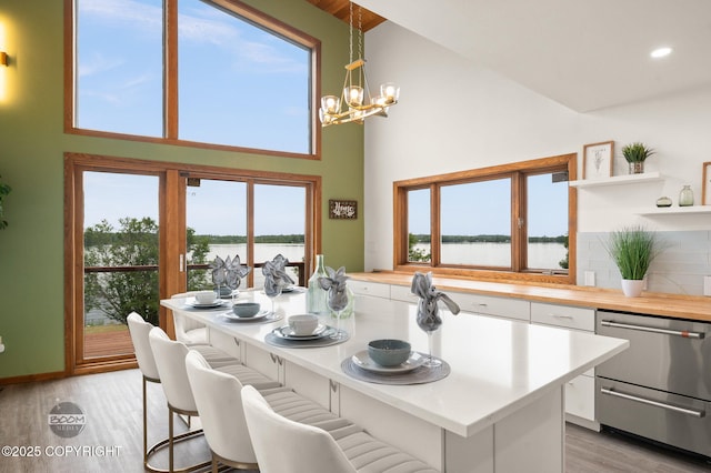900 W Selina Ln, Wasilla, AK 99654 - kitchen with dishwasher, white cabinets, high vaulted ceiling, light wood-style flooring, and a chandelier