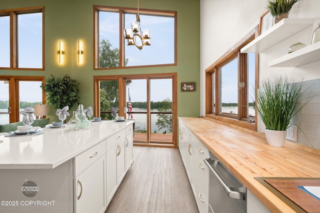 900 W Selina Ln, Wasilla, AK 99654 - kitchen featuring stainless steel dishwasher, plenty of natural light, white cabinetry, a towering ceiling, and a water view