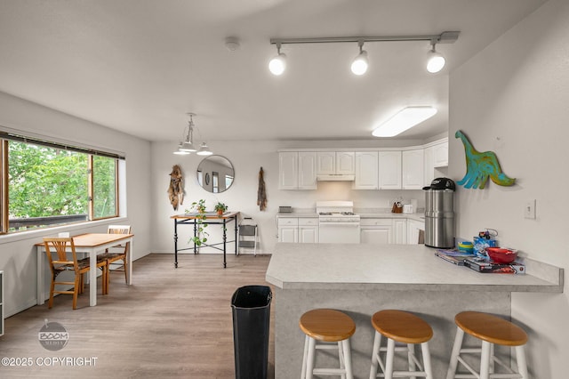 900 W Selina Ln, Wasilla, AK 99654 - kitchen featuring white gas range, a peninsula, white cabinets, a kitchen bar, and light countertops
