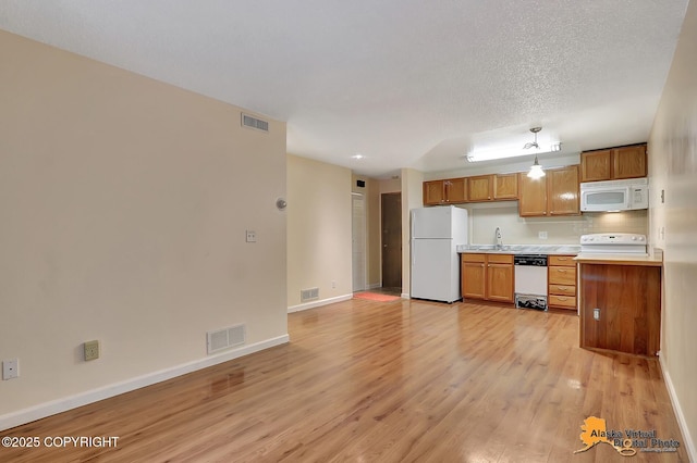 2210 Sentry Dr # B-18, Anchorage, AK 99507 - kitchen featuring white appliances, light wood-style flooring, light countertops, brown cabinets, and tasteful backsplash
