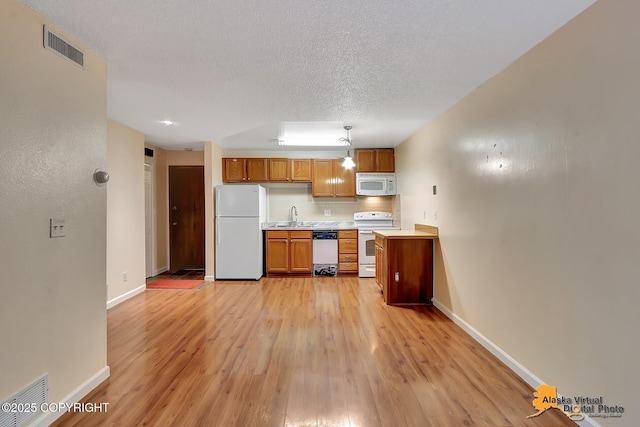 2210 Sentry Dr # B-18, Anchorage, AK 99507 - kitchen with white appliances, light countertops, light wood finished floors, brown cabinets, and a textured ceiling