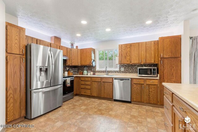 17311 Bonasila Cir, Eagle River, AK 99577 - kitchen with stainless steel appliances, brown cabinetry, light countertops, tasteful backsplash, and a textured ceiling