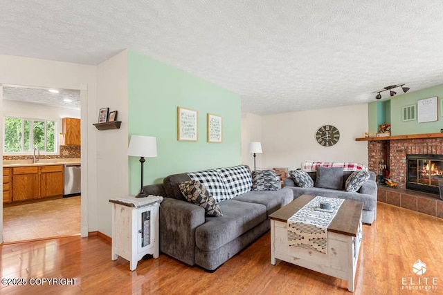 17311 Bonasila Cir, Eagle River, AK 99577 - living room featuring light wood-style floors, a textured ceiling, and a fireplace