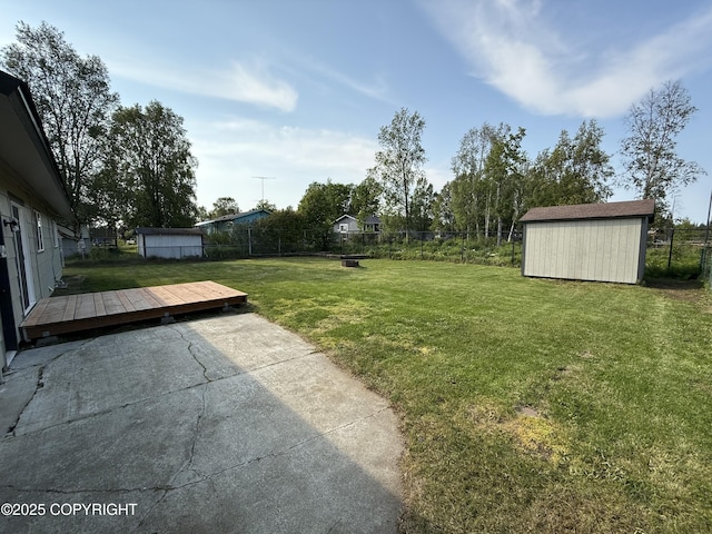1510 Fathom Dr, Kenai, AK 99611 - fenced backyard featuring a storage unit, a wooden deck, and a patio