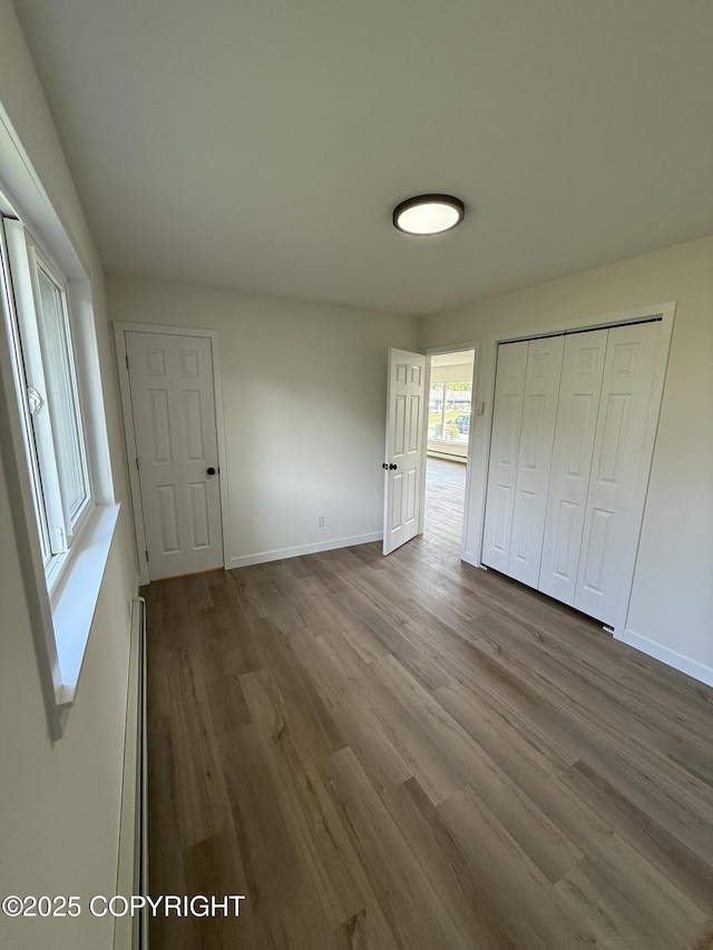1510 Fathom Dr, Kenai, AK 99611 - unfurnished bedroom featuring wood finished floors, a baseboard heating unit, and a closet