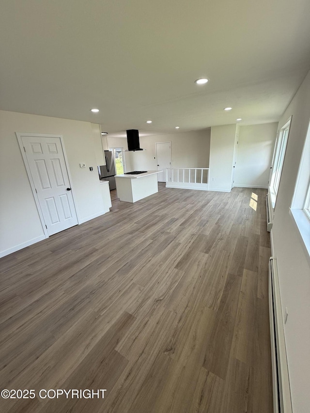 1510 Fathom Dr, Kenai, AK 99611 - unfurnished living room with a baseboard heating unit, wood finished floors, and recessed lighting