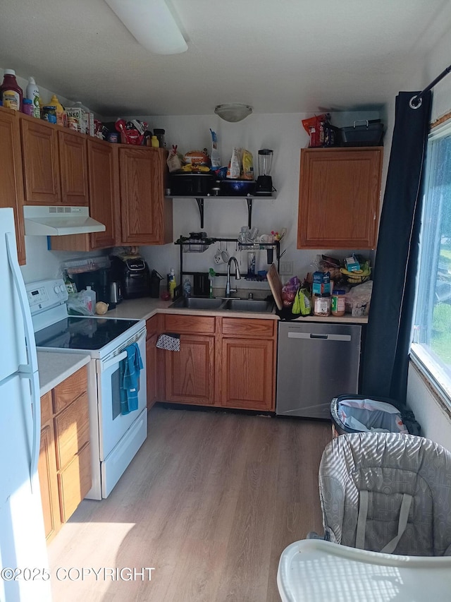 1011 Friendly Ln, Anchorage, AK 99504 - kitchen with white appliances, under cabinet range hood, light wood-style floors, light countertops, and brown cabinetry