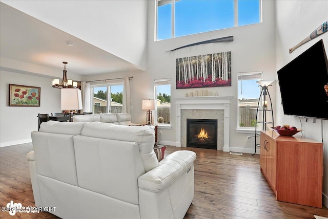 339 Skwentna Dr # 24, Anchorage, AK 99504 - living area with wood finished floors, a glass covered fireplace, a chandelier, a towering ceiling, and healthy amount of natural light