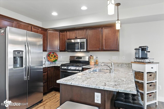 339 Skwentna Dr # 24, Anchorage, AK 99504 - kitchen featuring appliances with stainless steel finishes, a peninsula, light wood-style flooring, a kitchen breakfast bar, and recessed lighting