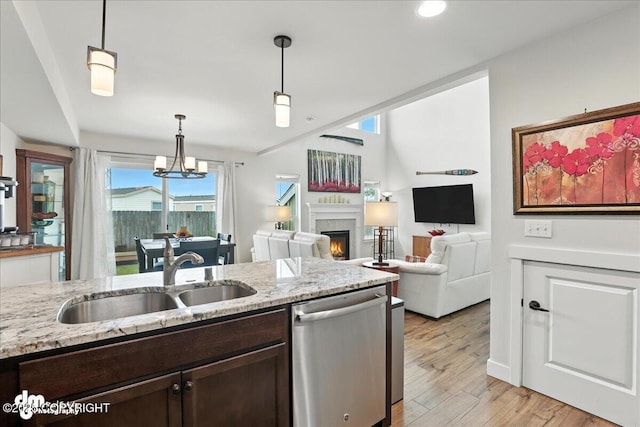 339 Skwentna Dr # 24, Anchorage, AK 99504 - kitchen featuring stainless steel dishwasher, dark brown cabinetry, a lit fireplace, decorative light fixtures, and light wood-style floors