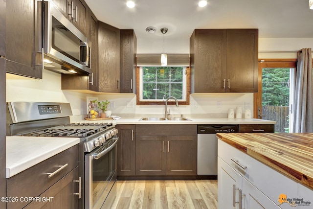 6312 Air Guard Rd, Anchorage, AK 99502 - kitchen featuring stainless steel appliances, dark brown cabinetry, light wood-type flooring, decorative light fixtures, and wood counters