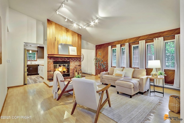 6312 Air Guard Rd, Anchorage, AK 99502 - living room with track lighting, wood walls, light wood-style flooring, a baseboard heating unit, and a brick fireplace