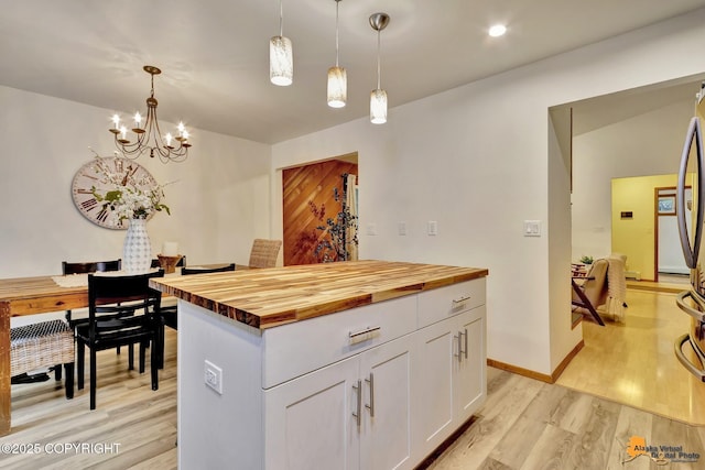 6312 Air Guard Rd, Anchorage, AK 99502 - kitchen with wood counters, white cabinetry, light wood-style floors, and hanging light fixtures