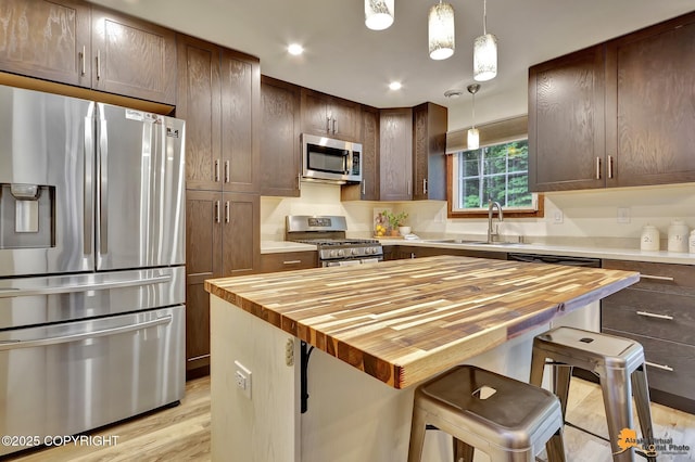 6312 Air Guard Rd, Anchorage, AK 99502 - kitchen with appliances with stainless steel finishes, butcher block counters, a breakfast bar area, pendant lighting, and recessed lighting