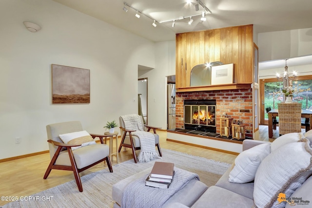 6312 Air Guard Rd, Anchorage, AK 99502 - living room featuring rail lighting, a fireplace, light wood-style floors, and a chandelier
