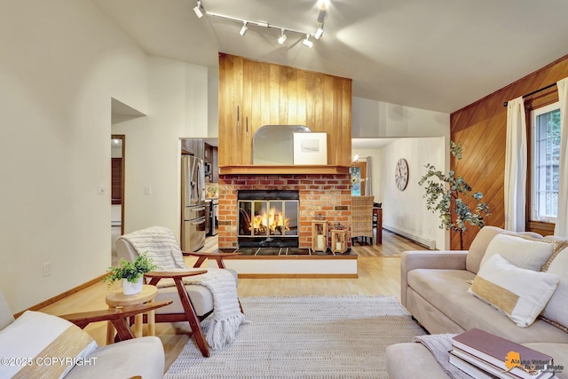 6312 Air Guard Rd, Anchorage, AK 99502 - living area featuring track lighting, light wood finished floors, a brick fireplace, high vaulted ceiling, and wooden walls