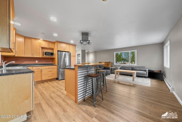 1740 Patterson Ct, Anchorage, AK 99504 - kitchen featuring stainless steel appliances, light brown cabinetry, baseboard heating, a breakfast bar, and dark countertops