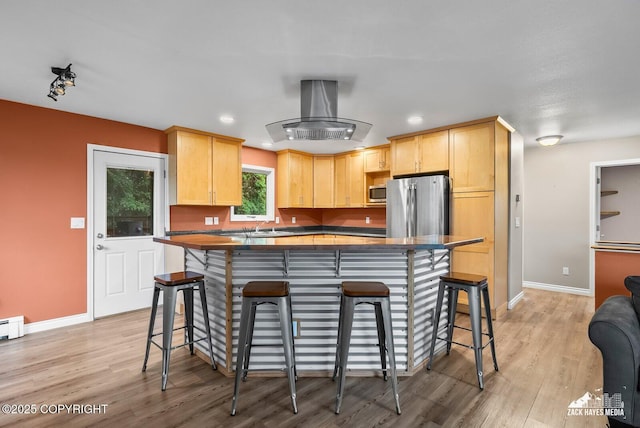 1740 Patterson Ct, Anchorage, AK 99504 - kitchen with appliances with stainless steel finishes, light brown cabinets, island exhaust hood, light wood-style flooring, and a center island