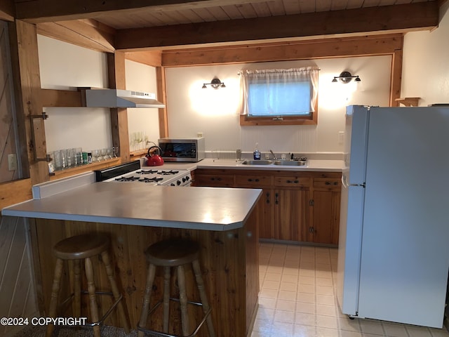 37905 Hall Rd, Sterling, AK 99672 - kitchen featuring white appliances, under cabinet range hood, a breakfast bar area, a peninsula, and brown cabinets