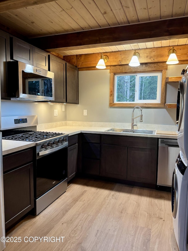37905 Hall Rd, Sterling, AK 99672 - kitchen featuring stainless steel appliances, stacked washer and clothes dryer, light wood finished floors, a wooden ceiling with exposed beams, and light countertops