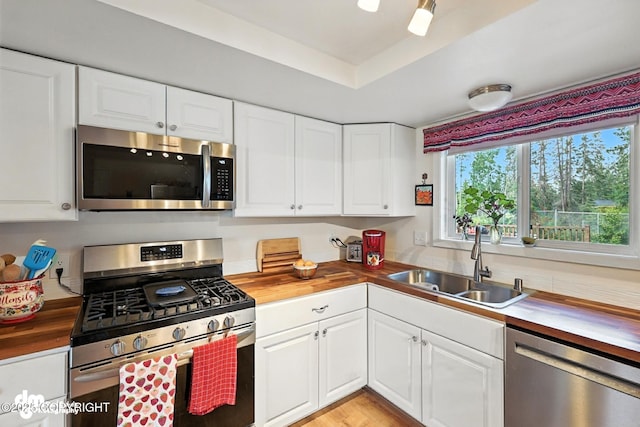 222 Crest Dr, Soldotna, AK 99669 - kitchen with stainless steel appliances, wood counters, white cabinetry, and a raised ceiling