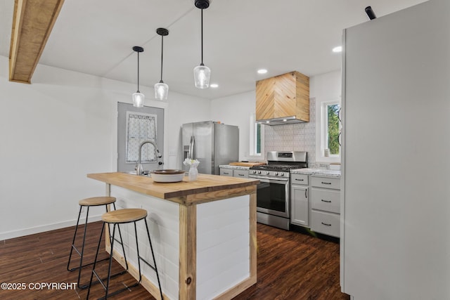 38835 Pinewood Ave, Sterling, AK 99672 - kitchen featuring appliances with stainless steel finishes, butcher block counters, custom range hood, a kitchen bar, and decorative backsplash