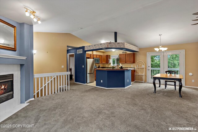 1220 S Felton St, Palmer, AK 99645 - kitchen featuring stainless steel appliances, brown cabinetry, vaulted ceiling, light colored carpet, and a kitchen island