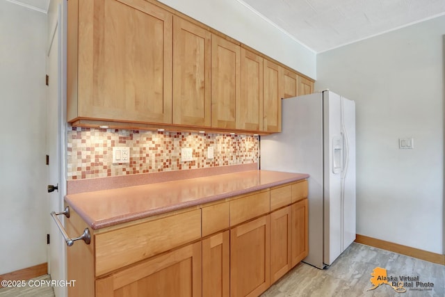 1110 F St, Anchorage, AK 99501 - kitchen with light brown cabinets, decorative backsplash, white fridge with ice dispenser, light countertops, and light wood-type flooring