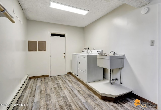 1110 F St, Anchorage, AK 99501 - washroom featuring baseboard heating, washer and dryer, light wood-style floors, and a textured ceiling