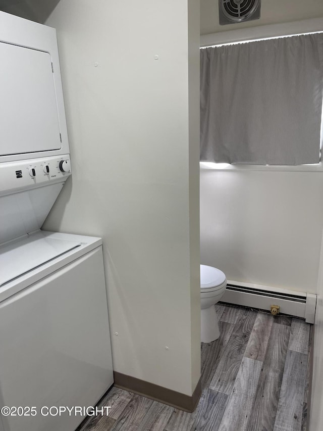 1110 F St, Anchorage, AK 99501 - laundry area featuring a baseboard radiator, stacked washer and clothes dryer, and wood finished floors