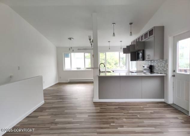 7141 Weimer Rd # 46, Anchorage, AK 99502 - kitchen with wood finished floors, a baseboard heating unit, a peninsula, light countertops, and backsplash